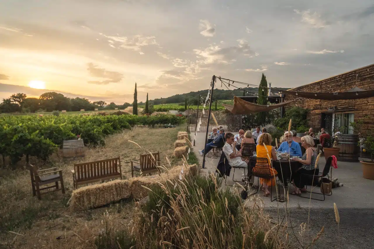 Dîner en plein air au coucher du soleil sur la terrasse du Domaine Allegria, avec vue sur les vignes et les bottes de foin