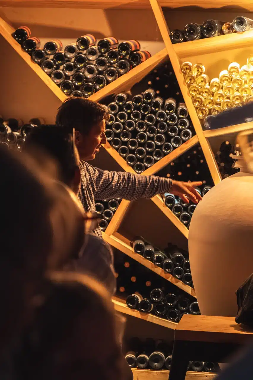 Le vigneron du Domaine Allegria présentant sa collection de vins dans l'œnothèque lors d'une visite guidée à Pézenas